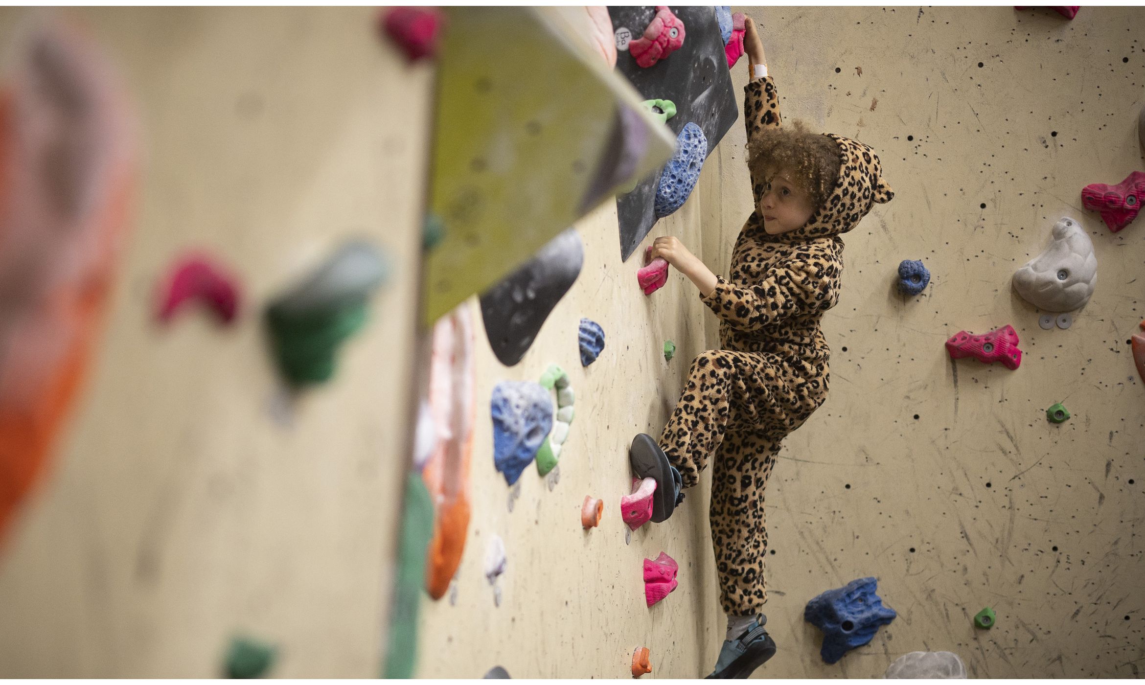 4 year old Kid bouldering wearing a leopard onesie 